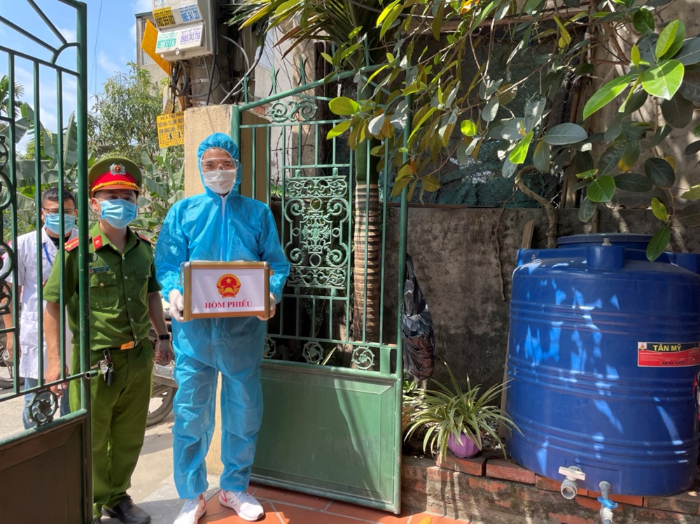 Cử tri phường Hà Khánh, TP Hạ Long đang thực hiện cách ly tại nhà được thành viên tổ bầu cử mang hòm phiếu phụ đến nhà để thực hiện quyền bầu cử.